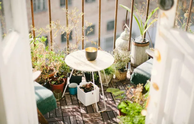 Gemütlicher Balkon mit Bistrotisch, Kerze und vielen Topfpflanzen